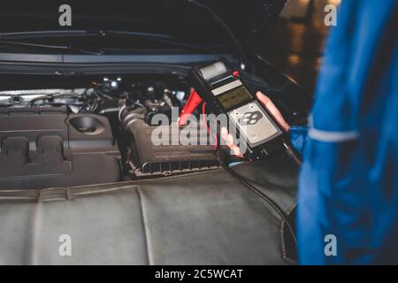 Un mécanicien automatique vérifie l'état de la batterie du véhicule. Contrôle du concept du système électrique du véhicule Banque D'Images