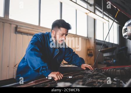 Mécanicien de voiture pensive à la recherche d'un problème de dysfonctionnement du moteur. Concept de réparation de voiture Banque D'Images