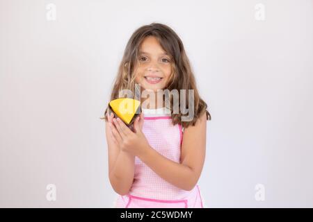 Jolie petite fille avec un tablier et manger un morceau de gâteau Banque D'Images