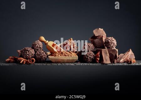 Truffes au chocolat avec des morceaux de chocolat. Le chocolat, les bâtons de cannelle et anis sur fond sombre. Copier l'espace. Banque D'Images