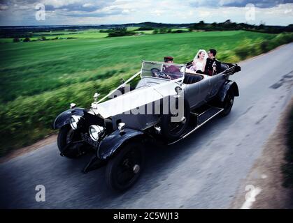 Rare années 1920 classique Rolls Royce argent Ghost voiture de mariage en mouvement. Mariée et marié conduit par chauffeur le jour de leur mariage. Banque D'Images