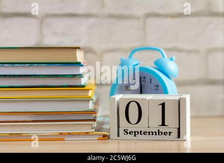 Retour à l'école, le 1er septembre sur le calendrier. Réveil et une pile de manuels sur la table Banque D'Images