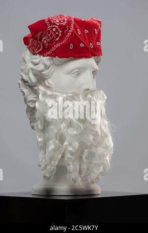 Statue en plâtre blanc d'un buste d'Apollo Belvedere avec une longue barbe blanche et un foulard de bandana rouge Banque D'Images