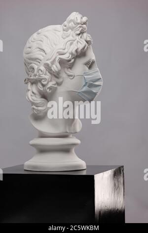Statue en plâtre blanc d'un buste d'Apollo Belvedere dans un masque médical de protection jetable couvrant son visage Banque D'Images