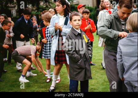 Enfants d'école avec un garçon portant un imperméable debout dans une ligne à la journée de sport scolaire, International School, Hambourg, Allemagne dans les années 1960 Banque D'Images