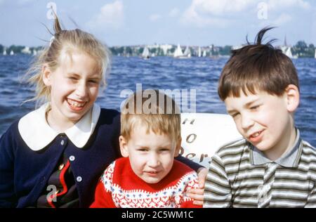 Famille de trois enfants dans un pédalo sur le lac Alster, Hambourg, Allemagne dans les années 1960, par une journée ensoleillée et venteuse Banque D'Images