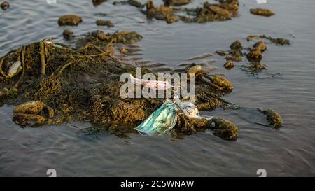 Les déchets plastiques du coronavirus polluent l'environnement. Les masques jetables sont des déchets dans l'océan. Jeté utilisé masque médical jetable flotte en soi Banque D'Images