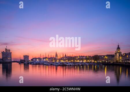 Vue panoramique sur le vieux port de la Rochelle au coucher du soleil avec ses célèbres tours anciennes. Magnifique ciel orange Banque D'Images