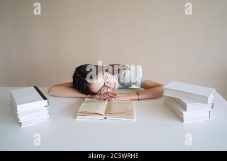 Une jeune fille adorable s'est endormie sur les livres quand elle a fait ses devoirs Banque D'Images