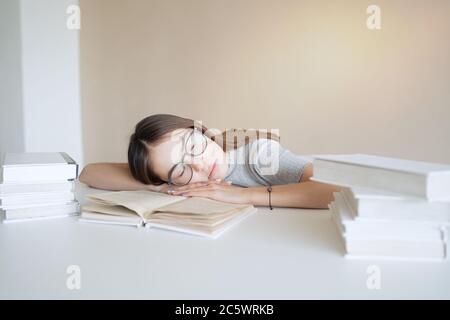 Une jeune fille adorable s'est endormie sur les livres quand elle a fait ses devoirs Banque D'Images