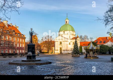 Varsovie, Pologne - 19 décembre 2019 : place du marché de la vieille ville avec célèbre église et fontaine d'eau et rue pavée et coucher de soleil bleu soleil Banque D'Images