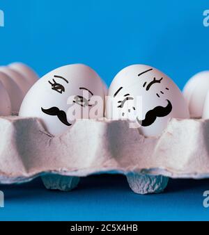 Visages sur les oeufs, couple gay dans le concept d'amour avec fond bleu Banque D'Images