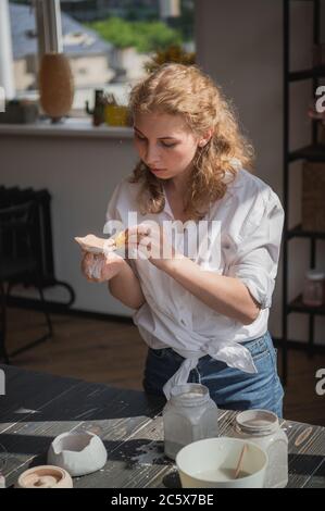 Processus de production de poterie. Application de la brosse glaçante sur les ustensiles en céramique. Banque D'Images