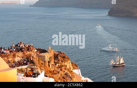 Touristes sur le toit d'une maison traditionnelle attendant le coucher de soleil étonnant à Santorin, île grecque, Grèce Banque D'Images