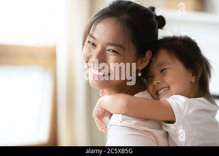 Petite petite petite petite petite petite fille asiatique d'âge préscolaire en cuddling de la maman arrière. Banque D'Images