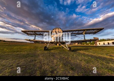 Vieux avion détruit dans le champ dans les rayons du soleil couchant avec de beaux nuages Banque D'Images