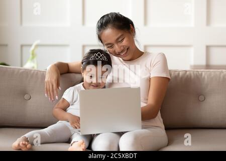 Petit bébé asiatique mignon utilisant un ordinateur avec maman. Banque D'Images