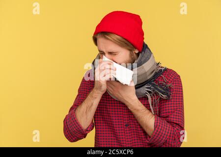 Malade dans un chapeau et un foulard chaud toux serviette éternuant, se sentir mal avec le nez qui coule, mal de gorge, souffrant d'allergie ou de symptômes de grippe saisonnière Banque D'Images