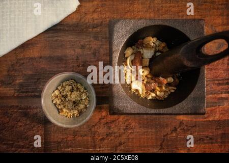 Vue de dessus des noix mélangées dans le mortier avec pilon et bol de granola avec fond texturé. Texture de la vie Banque D'Images