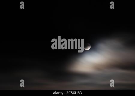 Pleine lune parmi un ciel sombre et des nuages Whispy Banque D'Images