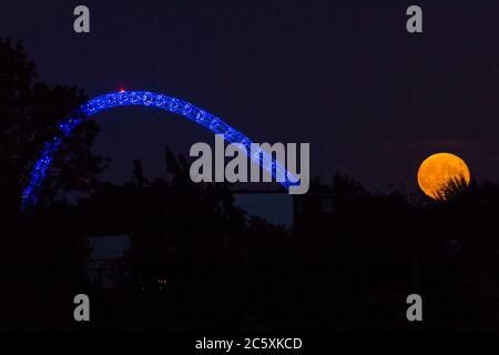 Wembley, Royaume-Uni. 5 juillet 2020. Météo britannique - la pleine lune de juillet, connue sous le nom de Buck Moon, s'élève derrière le stade Wembley dans le nord-ouest de Londres. Dans l'Almanac des fermiers, la Buck Moon est ainsi nommée d'après les nouveaux bois qui émergent d'un front de buck autour de cette période de l'année. L'arche du stade est illuminée en bleu pour commémorer le 72e anniversaire du National Health Service (NHS) et pour remercier tous les travailleurs du NHS pour leurs efforts pendant la pandémie de coronavirus. Credit: Stephen Chung / Alay Live News Banque D'Images