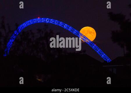 Wembley, Royaume-Uni. 5 juillet 2020. Météo britannique - la pleine lune de juillet, connue sous le nom de Buck Moon, s'élève derrière le stade Wembley dans le nord-ouest de Londres. Dans l'Almanac des fermiers, la Buck Moon est ainsi nommée d'après les nouveaux bois qui émergent d'un front de buck autour de cette période de l'année. L'arche du stade est illuminée en bleu pour commémorer le 72e anniversaire du National Health Service (NHS) et pour remercier tous les travailleurs du NHS pour leurs efforts pendant la pandémie de coronavirus. Credit: Stephen Chung / Alay Live News Banque D'Images