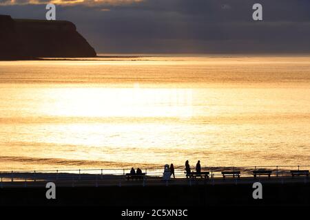 Le soleil commence à se coucher derrière un ciel nuageux à Whitby, dans le North Yorkshire Banque D'Images