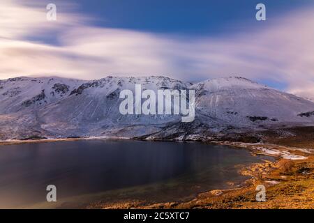 Photo d'un lac de montagne en exposition prolongée contre des montagnes enneigées au coucher du soleil en hiver, Esquel, Patagonie, Argentine Banque D'Images