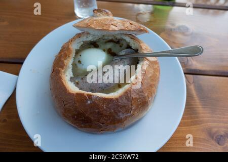 Soupe traditionnelle polonaise Zurek sour dans une boule de pain avec œufs et saucisses à l'intérieur, servie dans le restaurant Karczma Spalska. Spala Pologne centrale Banque D'Images