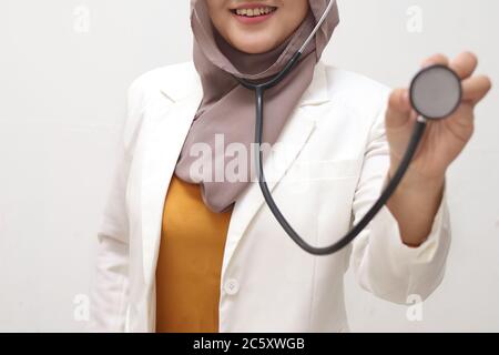 Belle asiatique musulmane médecin médecin portant hijab veulent faire l'examen avec stéthoscope, sourire à la caméra, sourire tortueuse Banque D'Images