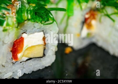Petits pains avec du poisson, du fromage et des algues vertes. Un plat traditionnel japonais. Gros plan Banque D'Images