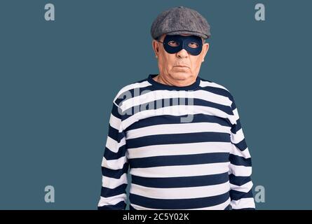 Homme de main senior portant un masque de cambriolage et t-shirt sceptique et nerveux, frowning bouleversé à cause du problème. Personne négative. Banque D'Images