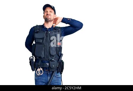 Jeune homme beau portant un uniforme de police souffrant de blessures de mal de cou, touchant le cou avec la main, douleur musculaire Banque D'Images