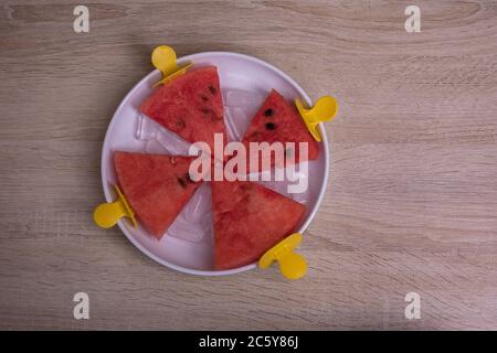 Tranches de pastèque dans un bol avec glace sur un bâton de glace sur fond de bois. Idée créative Banque D'Images