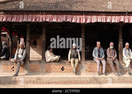 Quelques hommes népalais portant Dhaka Topi assis à un temple de la place Bhaktapur Durbar, au Népal Banque D'Images