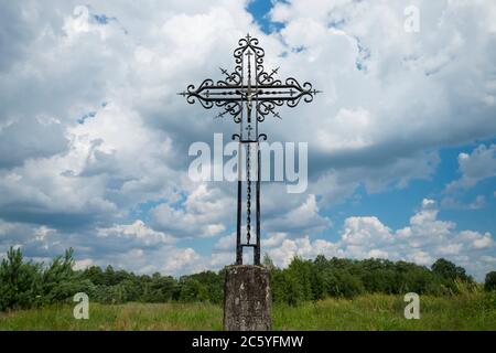 Une croix chrétienne en fer forgé contre le ciel dans le cimetière utilisé par les nazis allemands pendant la Seconde Guerre mondiale comme lieu de sépulture pour ceux qui sont morts à proximité Banque D'Images