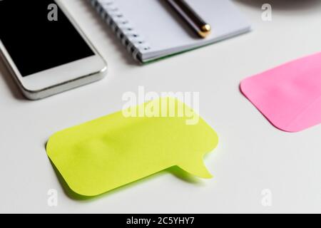 gros plan du bureau blanc, deux autocollants de couleur pour les notes, smartphone, ordinateur portable et stylo métallique, maquette d'entreprise Banque D'Images