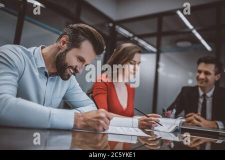 Homme souriant signant un document avec sa femme Banque D'Images