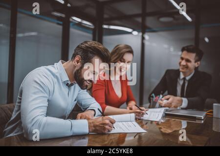 Homme souriant et sa femme signant un contrat Banque D'Images