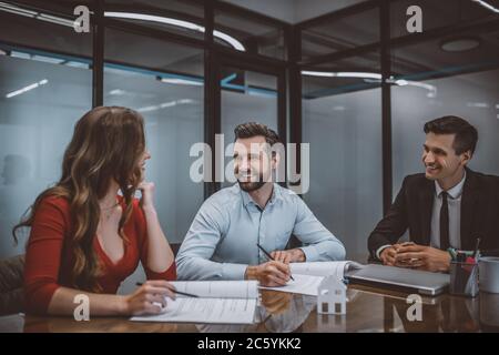 Heureux couple signant un contrat pour acheter une maison Banque D'Images