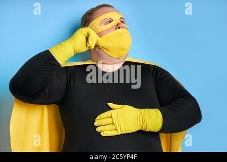 jeune homme de nettoyage de graisse caucasien en costume de super-héros et en masque, il est prêt à sauver la planète de la saleté. isolé sur fond bleu Banque D'Images