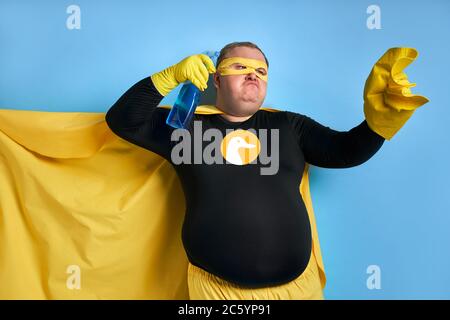 angry caucasien gras homme en costume jaune applique le détergent au chiffon, il est fatigué de la saleté. concept de nettoyage Banque D'Images