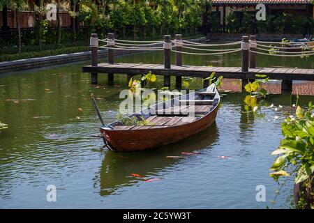 Bateau en bois sur l'étang près de la jetée dans un jardin tropical à Danang, Vietnam. Concept de voyage et de nature Banque D'Images