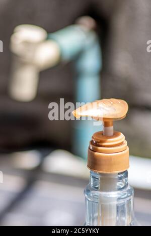 Un robinet et un détergent à vaisselle dans la cuisine extérieure. Un robinet en gros plan et une bouteille en plastique avec un liquide de désinfection ou du savon. Banque D'Images