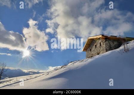 chalet alpin traditionnel au sommet de la montagne enneigée sous le soleil levant dans le ciel Banque D'Images