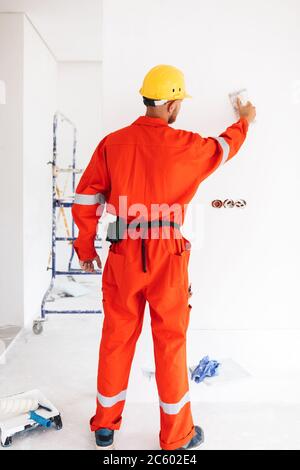 Jeune contremaître debout de l'arrière dans des vêtements de travail orange et Banque D'Images