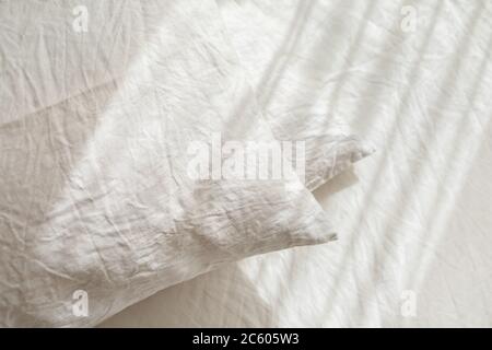 Linge de lit en tissu blanc. Pile d'oreillers. Chambre intérieure confortable et belle lumière du matin. Couleur pastel. Linge naturel bio tendance. Banque D'Images