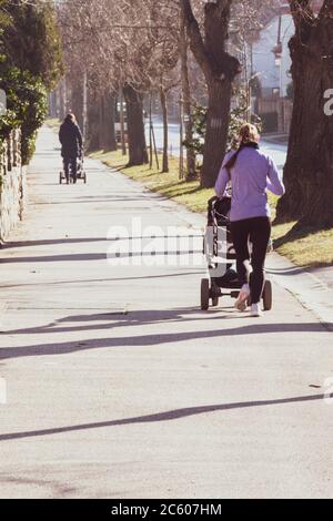 Deux mères poussant des prams dans la rue en hiver, vue arrière, Sopron, Hongrie Banque D'Images