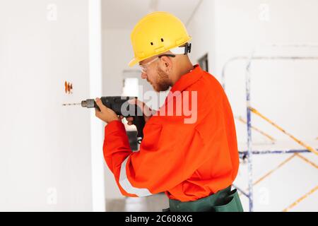 Jeune contremaître en vêtements de travail orange et chapeau rigide jaune avec un el Banque D'Images