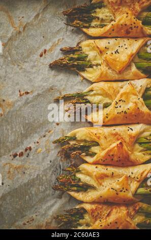 Asperges vertes cuites au fromage, enveloppées de pâte feuilletée. Placé sur du papier de cuisson avec espace pour les copies